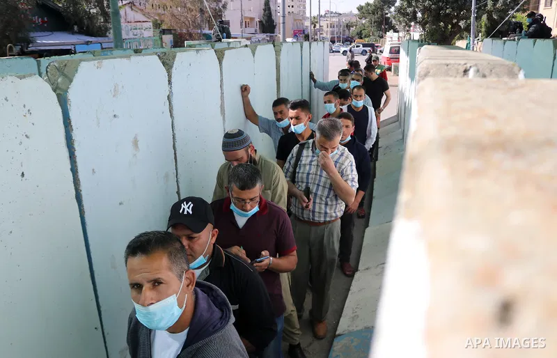 Members of the Israeli security forces stand guard as Palestinians wait to cross through the Bethlehem checkpoint in the West Bank to Jerusalem, to attend the second Friday prayers of the fasting month of Ramadan at the...