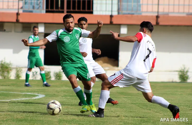 Palestinian football players of Al-Shejaiya Union (green) and Gaza Sports (White) compete during match of the Al-Quds Ramadan Championship, at Palestine Stadium in Gaza City, on April 25, 2021. Photo by Marihan Al-Khalid...