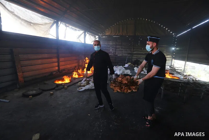 Palestinian chefs cook chickens and rice on firewood by burying them inside a barrel underground, to sell it to customers during the holy month of Ramadan in Deir al-Balah in the center of Gaza Strip, aimd the COVID-19 p...