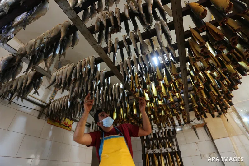 Palestinian men wearing masks, prepare Smoked Herring or, salted fish to be sold in markets days before of Eid al Fitr holiday in Nuseirat in the center of Gaza Strip on May 5, 2021. People flock markets and shopping mal...