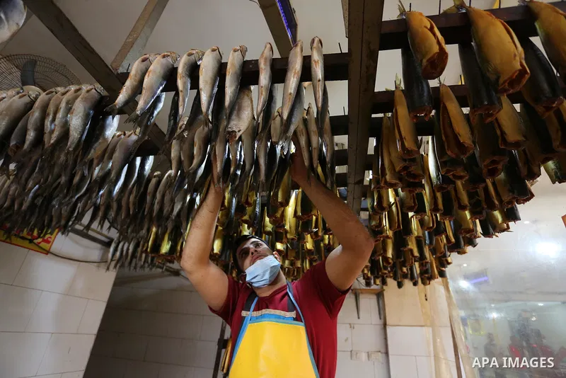 Palestinian men wearing masks, prepare Smoked Herring or, salted fish to be sold in markets days before of Eid al Fitr holiday in Nuseirat in the center of Gaza Strip on May 5, 2021. People flock markets and shopping mal...