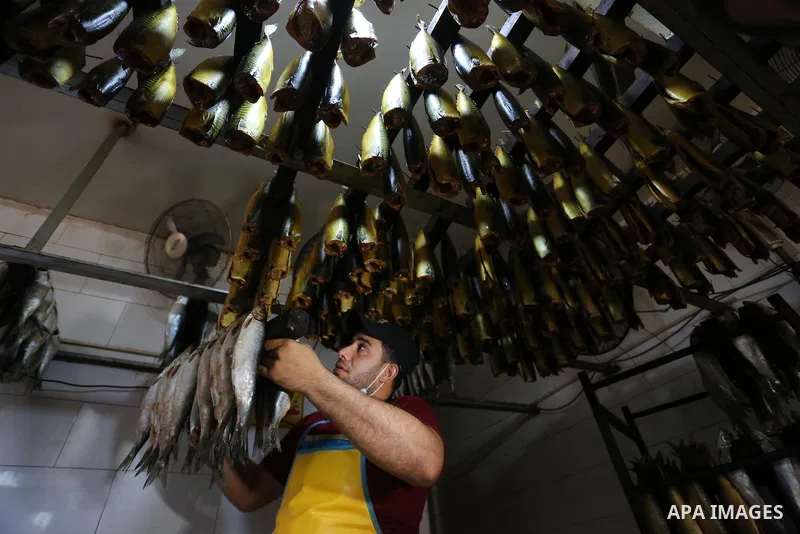 Palestinian men wearing masks, prepare Smoked Herring or, salted fish to be sold in markets days before of Eid al Fitr holiday in Nuseirat in the center of Gaza Strip on May 5, 2021. People flock markets and shopping mal...