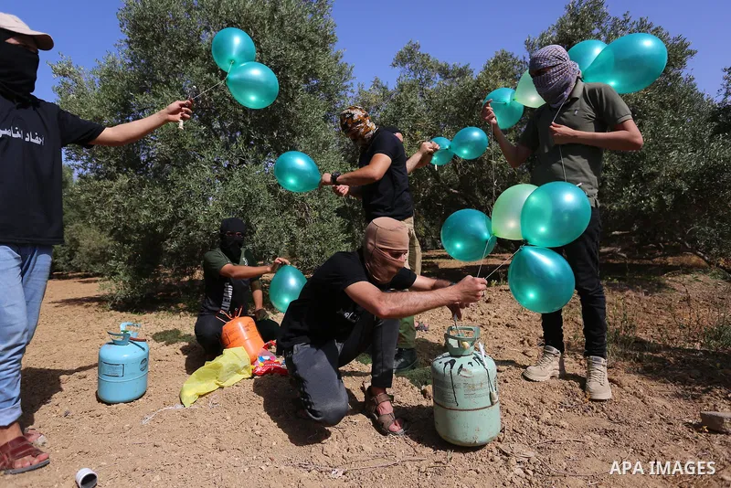 Masked Palestinian followers of the Al-Nasser Salah al-Din Brigades near Al-Bureij camp, in the center of the Gaza Strip, prepare to fly incendiary balloons across the eastern border toward Israel, on May 8, 2021, a day...