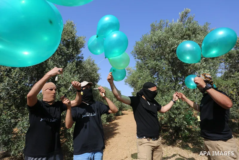 Masked Palestinian followers of the Al-Nasser Salah al-Din Brigades near Al-Bureij camp, in the center of the Gaza Strip, prepare to fly incendiary balloons across the eastern border toward Israel, on May 8, 2021, a day...