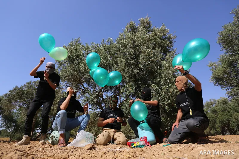 Masked Palestinian followers of the Al-Nasser Salah al-Din Brigades near Al-Bureij camp, in the center of the Gaza Strip, prepare to fly incendiary balloons across the eastern border toward Israel, on May 8, 2021, a day...