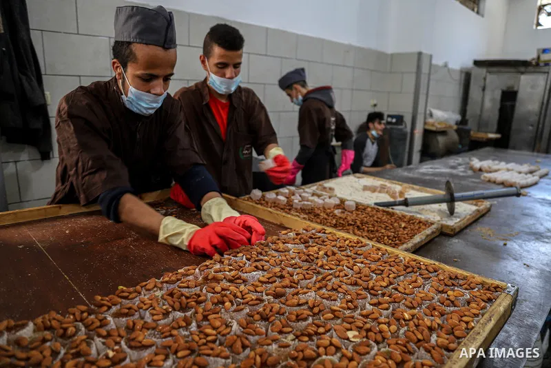 Palestinians prepare sweet known in Arabic as "Halkoum" to be sold ahead of the Eid al-Fitr holiday, at a factory in Gaza City on May 09, 2021. Eid al-Fitr this year is different in light of the COVID-19 pandemic. Eid al...