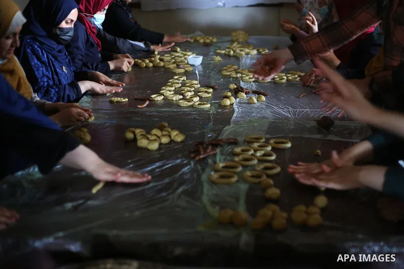 Palestinian deaf girls, wear protective and masks prepare traditional date-filled mini cakes, ahead of Eid al Fitr, at the Hamm Association, in the Maghazi camp, in the center of Gaza strip on May 10, 2021. Eid al-Fitr t...