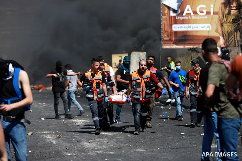 Demonstrators help an injured protester during q protest against Israel's occupation and its air campaign on the Gaza strip near the settlement of Beit El and Ramallah in the occupied West Bank on May 18, 2021. Heavy air...