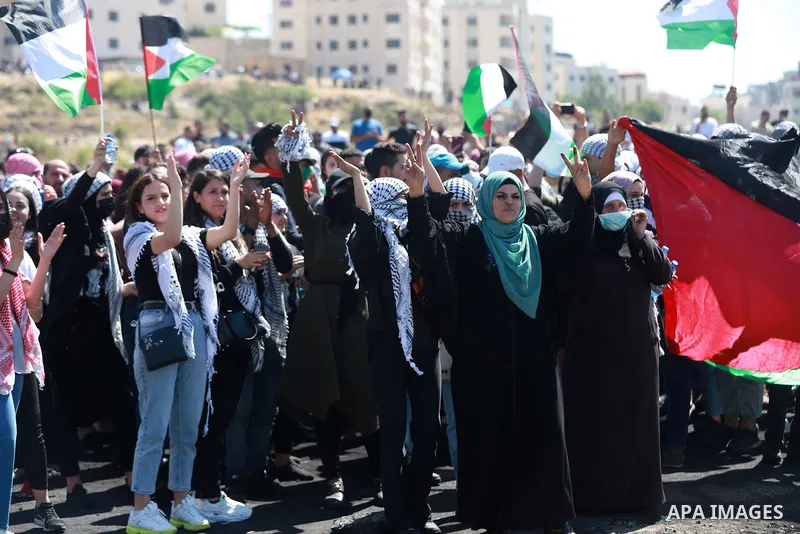 Palestinians protesting against Israel's occupation and its air campaign on the Gaza strip, shout slogans as they face Israeli troops near the settlement of Beit El and Ramallah in the occupied West Bank on May 18, 2021....