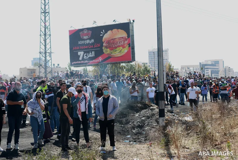 Palestinians protesting against Israel's occupation and its air campaign on the Gaza strip, shout slogans as they face Israeli troops near the settlement of Beit El and Ramallah in the occupied West Bank on May 18, 2021....