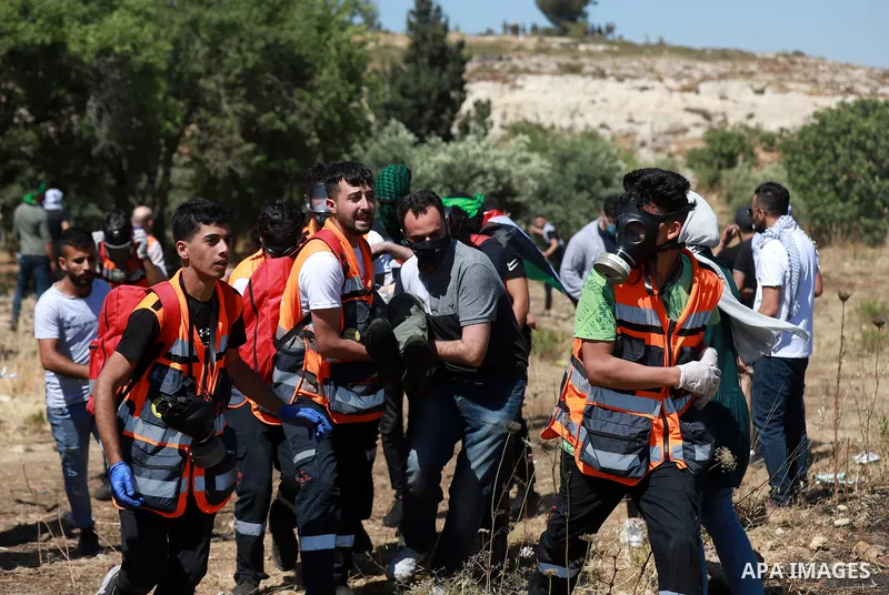 Demonstrators help an injured protester during q protest against Israel's occupation and its air campaign on the Gaza strip near the settlement of Beit El and Ramallah in the occupied West Bank on May 18, 2021. Heavy air...