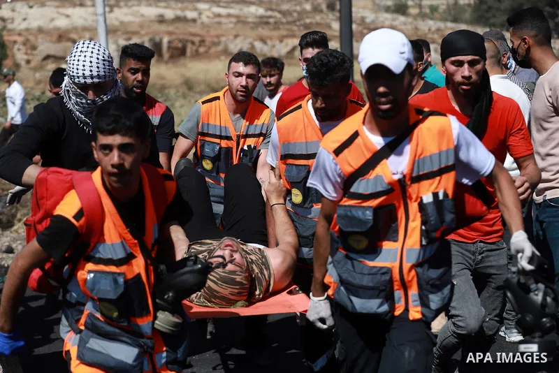 Demonstrators help an injured protester during q protest against Israel's occupation and its air campaign on the Gaza strip near the settlement of Beit El and Ramallah in the occupied West Bank on May 18, 2021. Heavy air...