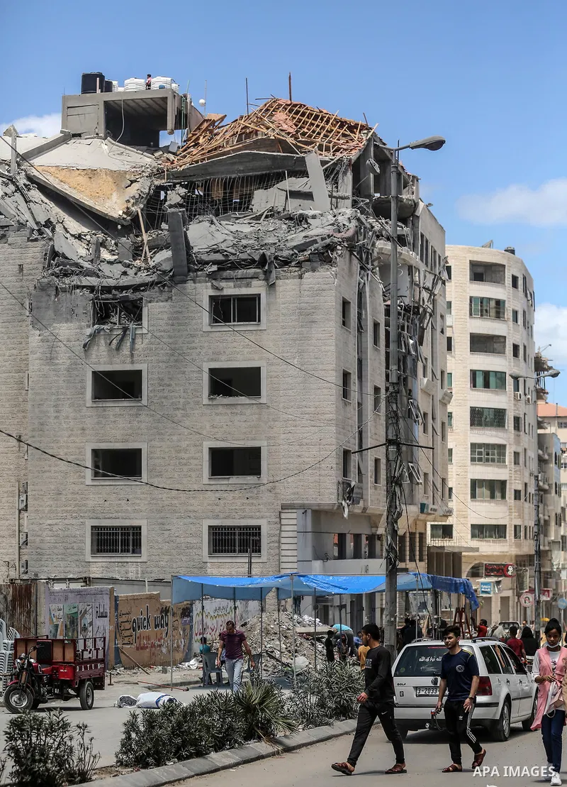 Palestinians walk past a building destroyed by Israeli missile strikes in Gaza City on May 22, 2021, following a ceasefire between Israel and Hamas movment. UNICEF delivered today lifesaving critical humanitarian supplie...
