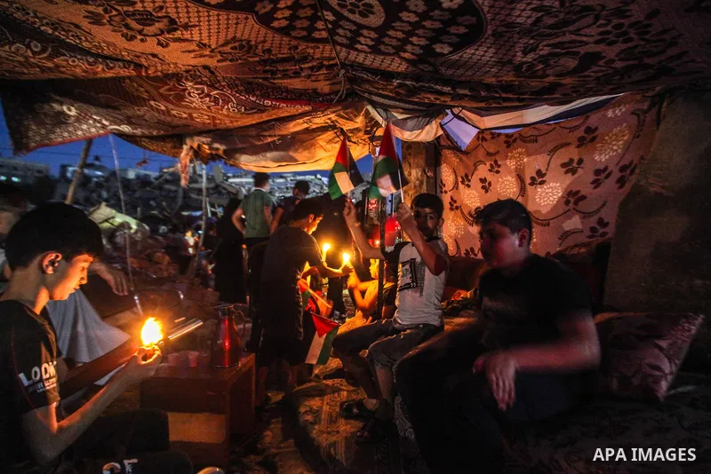 Palestinian Children hold candles during a rally amid the ruins of houses destroyed by Israeli strikes, in the northern of in Gaza strip, on May 24. 2021. Gazans tried to piece back their lives after a devastating 11-day...