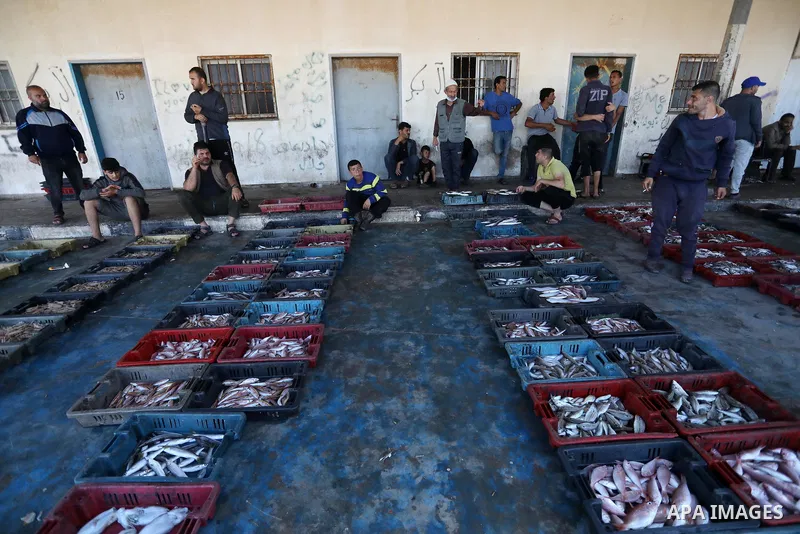 Palestinian fishermen sell fish and seafood for customers as the day's catch was auctioned off at Gaza City's main port, on May 25, 2021, after Israeli security forces allowed a limited number of Palestinian fishing boat...