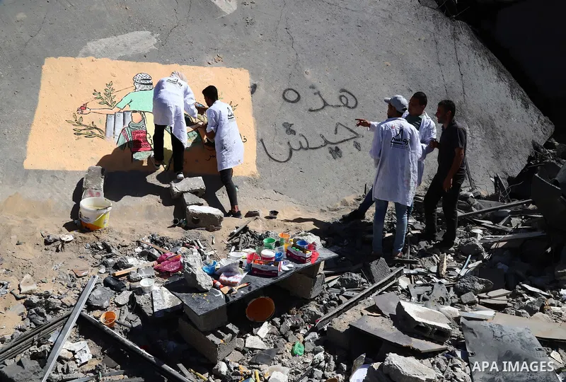Palestinian artists paint wall mural on the rubble of shorouq tower which was destroyed by Israeli air strike earlier this month, in Gaza City on May 25, 2021. A ceasefire was reached late last week after 11 days of dead...