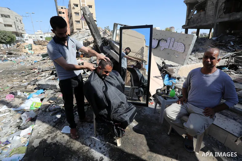 A Palestinian barber works next to the ruins of his shop which was destroyed by Israeli strikes, in Gaza City, on May 25, 2021. A ceasefire was reached late last week after 11 days of deadly violence between Israel and t...