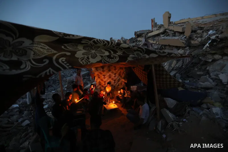 Palestinians sit in a tent that has been set up on top of the ruins of a building destroyed in recent Israeli air strikes, in Beit Lahia in the northern of Gaza strip, on May 25. 2021. Gaza’s housing ministry said on Thu...
