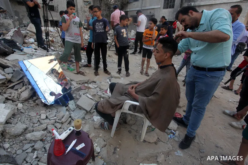 Palestinian barber works next to the ruins of his shop which was destroyed by Israeli strikes earlier this month, in Gaza City on May 26, 2021. A ceasefire was reached late last week after 11 days of deadly violence betw...