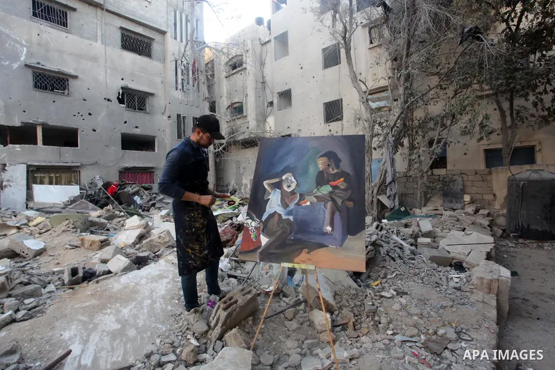 Palestinian artists paint on the rubble of Abu Hatab family house which was destroyed by Israeli air strike earlier this month, in Gaza City on May 26, 2021. A ceasefire was reached late last week after 11 days of deadly...