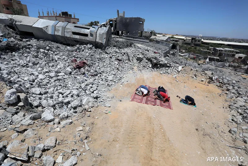 Palestinian Muslim worshippers pray near the rubble of a mosque which was destroyed by Israeli air strikes in Beit Lahia, in the northern Gaza Strip on May 27, 2021. A ceasefire was reached late last week after 11 days o...