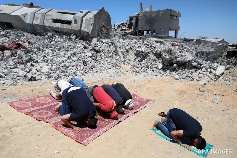 Palestinian Muslim worshippers pray near the rubble of a mosque which was destroyed by Israeli air strikes in Beit Lahia, in the northern Gaza Strip on May 27, 2021. A ceasefire was reached late last week after 11 days o...