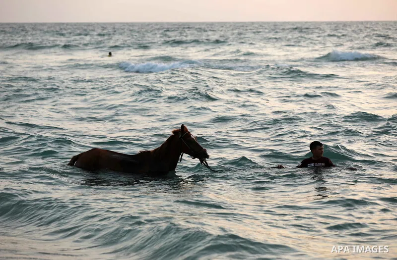 Palestinians spend time at the beach to escape the hot weather and the ongoing power cuts, in Deir al-Balah in the center of Gaza Strip on May 28, 2021. Photo by Ashraf Amra