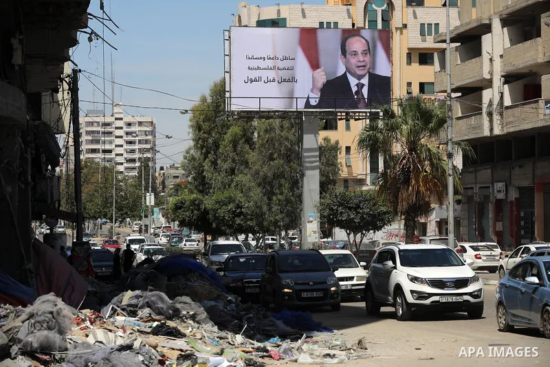 Palestinians walk past a poster of the Egyptian President Abdel Fattah el-Sisi, in Gaza city on May 30, 2021. Egypt has brokered a ceasefire agreement to end the Israeli airstrikes on the Gaza Strip, which have killed mo...