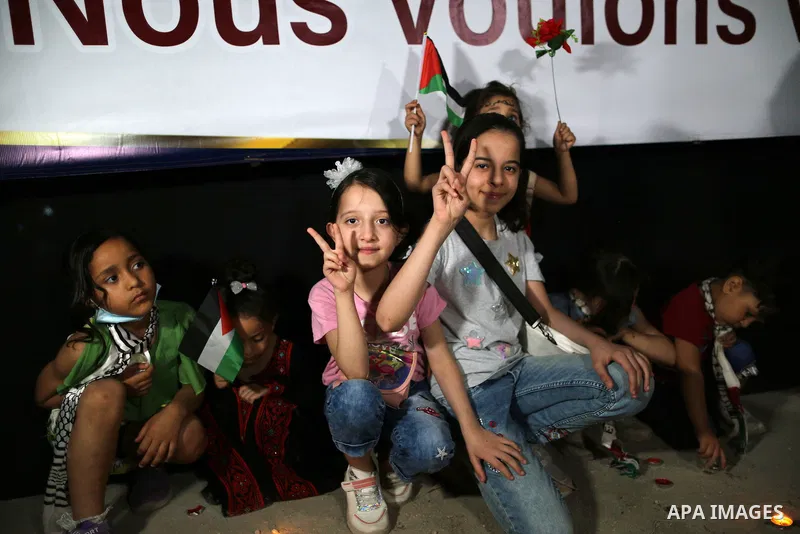Palestinian children take part in a rally to light candles amid the ruins of houses destroyed by Israeli strikes, in Gaza City on May 30, 2021. The Egyptian-brokered truce ended 11 days of heavy Israeli bombing of Gaza a...