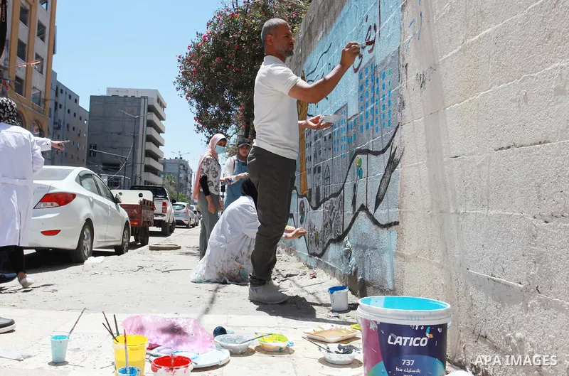 Artists paint wall mural as the Palestinian Artists Association take part in a protest against the destroyed of their headquarters by Israeli air strikes, in front of al-Jawhara tower, in Gaza City on June 6, 2021. Gaza’...