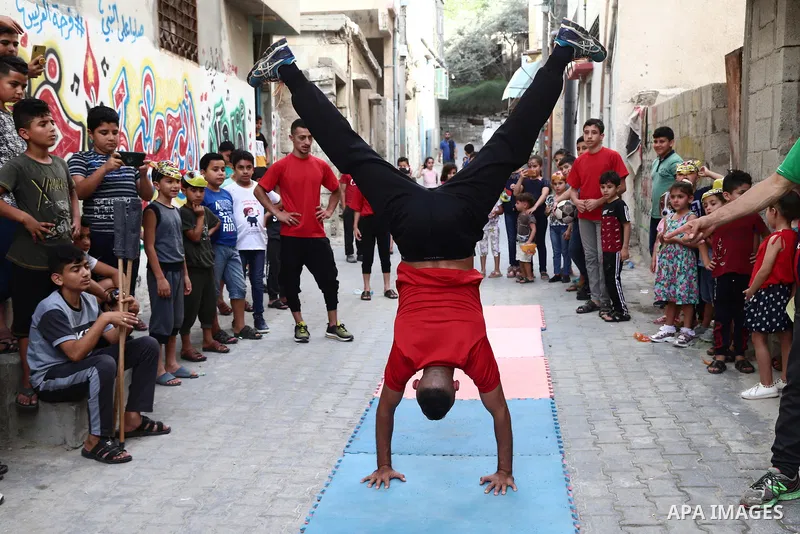 Palestinian volunteers perform acrobatic show in front of children during a mental health support session in Gaza city on June 9, 2021. As Gaza tries to recover from the deadly 11-day Israeli attack, mothers and mental h...