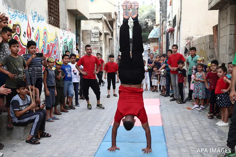 Palestinian volunteers perform acrobatic show in front of children during a mental health support session in Gaza city on June 9, 2021. As Gaza tries to recover from the deadly 11-day Israeli attack, mothers and mental h...