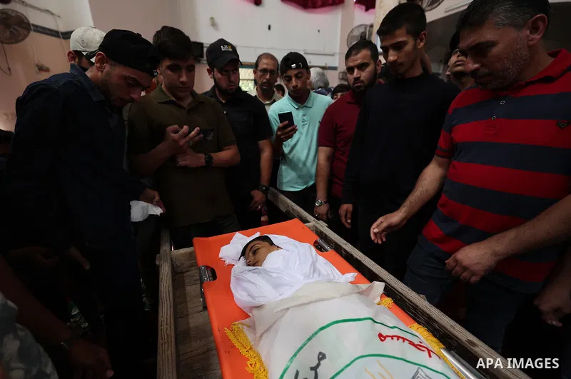 Relatives of Palestinian boy Obaida Dahdoh, who was killed by unexploded projectiles, mourn as they gather around his body during his funeral in Gaza City on June 10, 2021. Photo by Osama Baba
