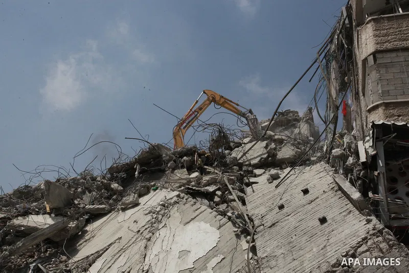 Egyptian workers and bulldozers sent from Egypt help to remove the rubble of Shorouq tower destroyed by Israeli air strikes last month in Gaza City on June 10, 2021. After brokering a ceasefire between the Israelis and H...