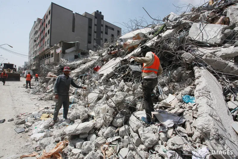 Egyptian workers and bulldozers sent from Egypt help to remove the rubble of Shorouq tower destroyed by Israeli air strikes last month in Gaza City on June 10, 2021. After brokering a ceasefire between the Israelis and H...