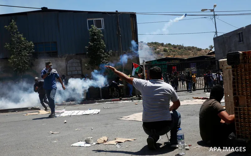 Palestinian demonstrators run to take cover from tear gas canisters fired by Israeli security forces during clashes following a protest against Israeli settlements in the village of Beita near the West Bank city of Nablu...