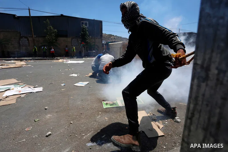 Palestinian demonstrators run to take cover from tear gas canisters fired by Israeli security forces during clashes following a protest against Israeli settlements in the village of Beita near the West Bank city of Nablu...