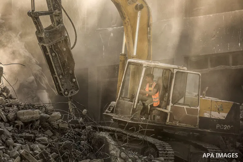 Egyptian workers and bulldozers sent from Egypt help to remove the rubble of Shorouq tower destroyed by Israeli air strikes last month in Gaza City on June 20, 2021. Photo by Bashar Taleb