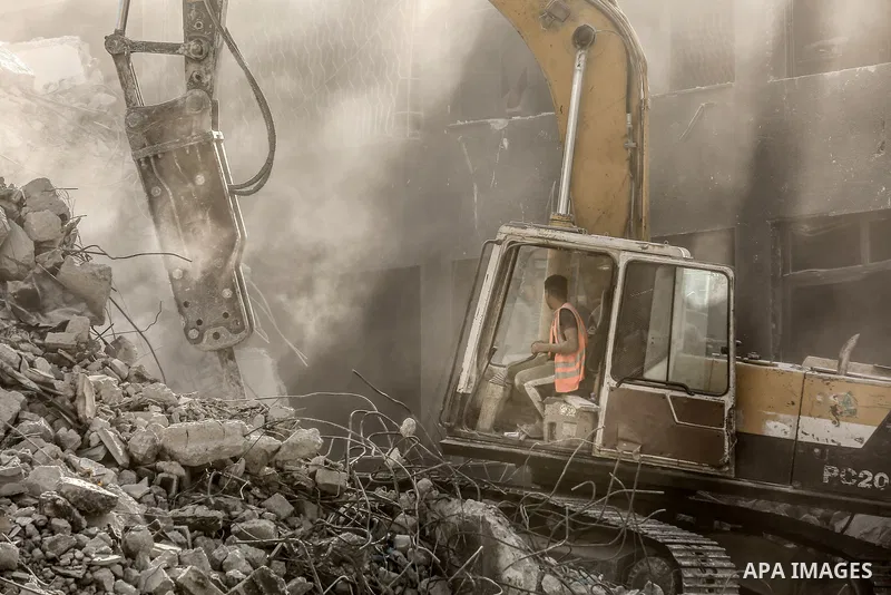 Egyptian workers and bulldozers sent from Egypt help to remove the rubble of Shorouq tower destroyed by Israeli air strikes last month in Gaza City on June 20, 2021. Photo by Bashar Taleb