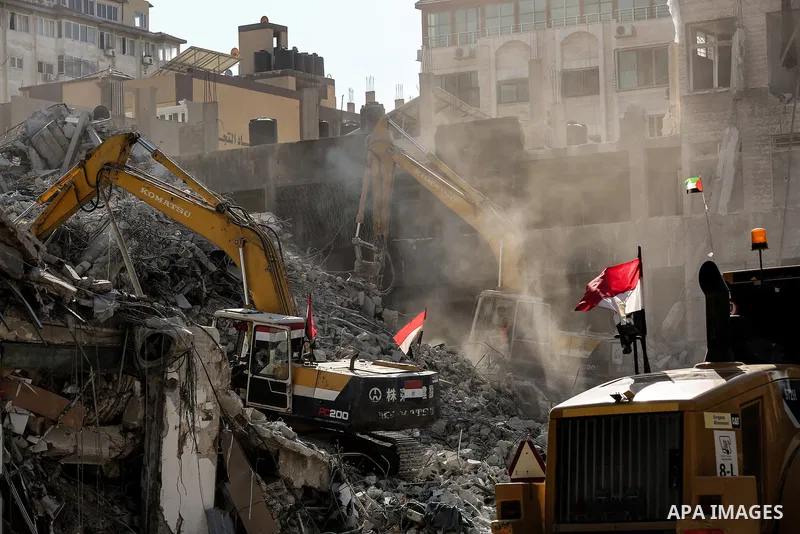 Egyptian workers and bulldozers sent from Egypt help to remove the rubble of Shorouq tower destroyed by Israeli air strikes last month in Gaza City on June 20, 2021. Photo by Bashar Taleb