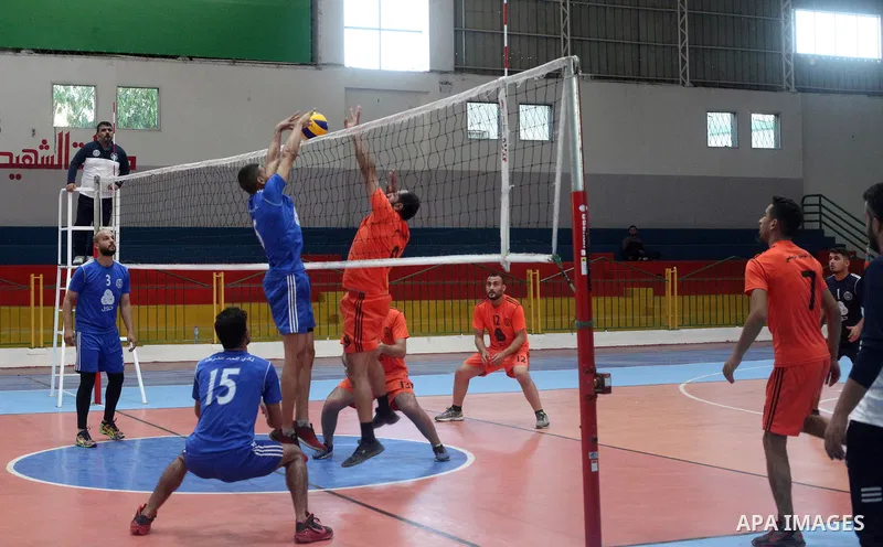 Palestinian players of police team (blue) and players of al-Wafaq team (orange) in actions during Volleyball match in Gaza city on June 20, 2021. Photo by Ali Hamad