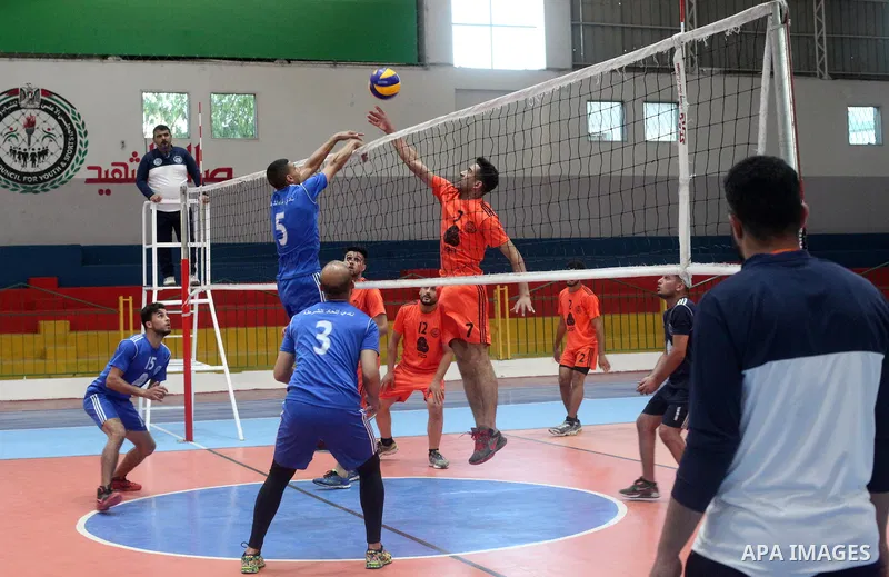 Palestinian players of police team (blue) and players of al-Wafaq team (orange) in actions during Volleyball match in Gaza city on June 20, 2021. Photo by Ali Hamad