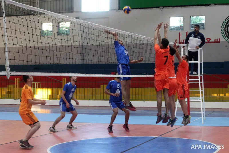 Palestinian players of police team (blue) and players of al-Wafaq team (orange) in actions during Volleyball match in Gaza city on June 20, 2021. Photo by Ali Hamad