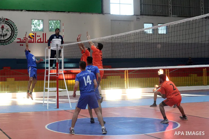 Palestinian players of police team (blue) and players of al-Wafaq team (orange) in actions during Volleyball match in Gaza city on June 20, 2021. Photo by Ali Hamad