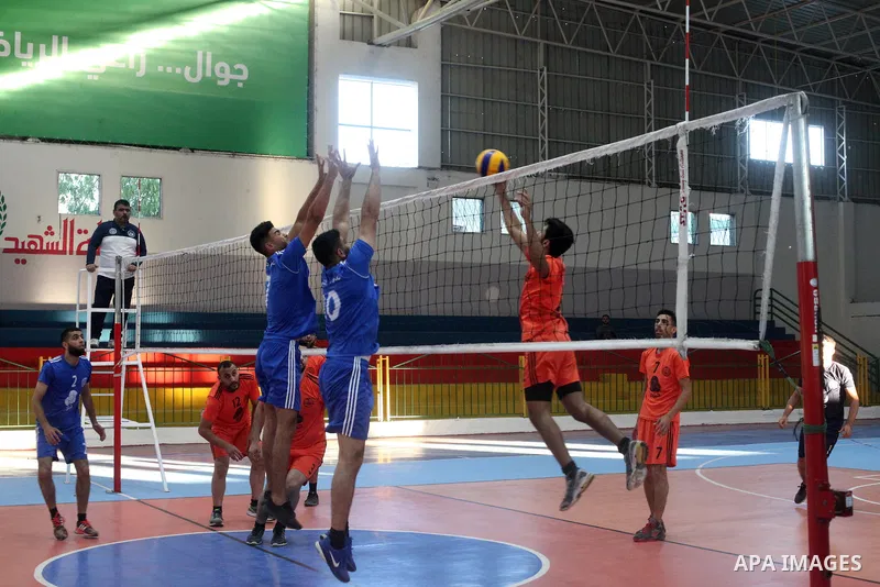 Palestinian players of police team (blue) and players of al-Wafaq team (orange) in actions during Volleyball match in Gaza city on June 20, 2021. Photo by Ali Hamad