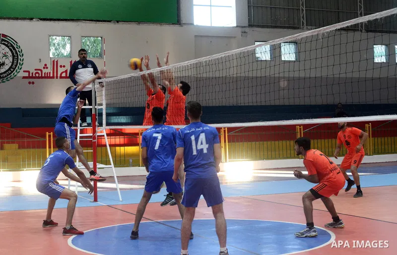 Palestinian players of police team (blue) and players of al-Wafaq team (orange) in actions during Volleyball match in Gaza city on June 20, 2021. Photo by Ali Hamad