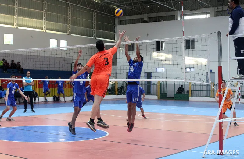 Palestinian players of police team (blue) and players of al-Wafaq team (orange) in actions during Volleyball match in Gaza city on June 20, 2021. Photo by Ali Hamad