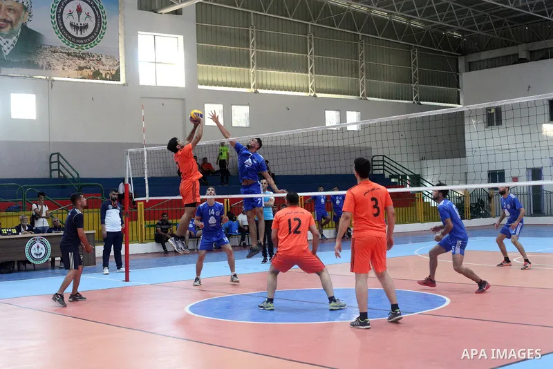 Palestinian players of police team (blue) and players of al-Wafaq team (orange) in actions during Volleyball match in Gaza city on June 20, 2021. Photo by Ali Hamad