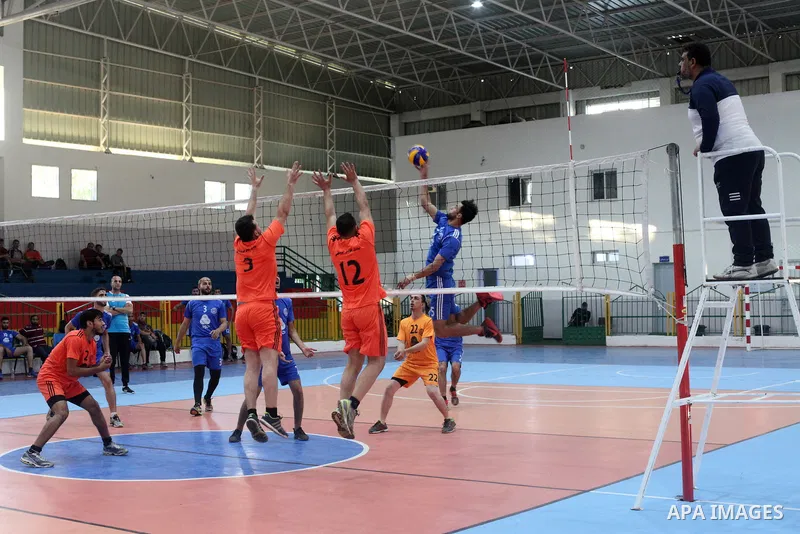 Palestinian players of police team (blue) and players of al-Wafaq team (orange) in actions during Volleyball match in Gaza city on June 20, 2021. Photo by Ali Hamad