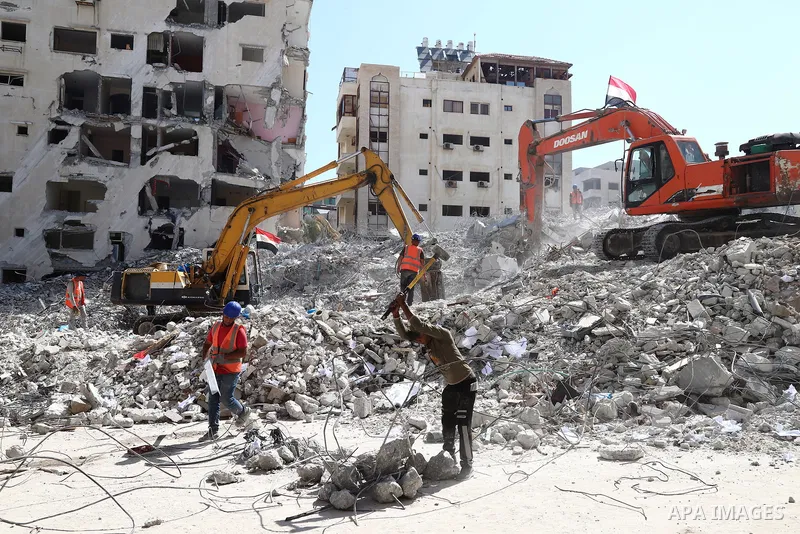 Egyptian bulldozers and Palestinian workers remove the rubbles of Hanadi Tower destroyed by Israeli air strikes last month in Gaza City on June 21, 2021. Gaza’s housing ministry said on that 16,800 housing units had been...
